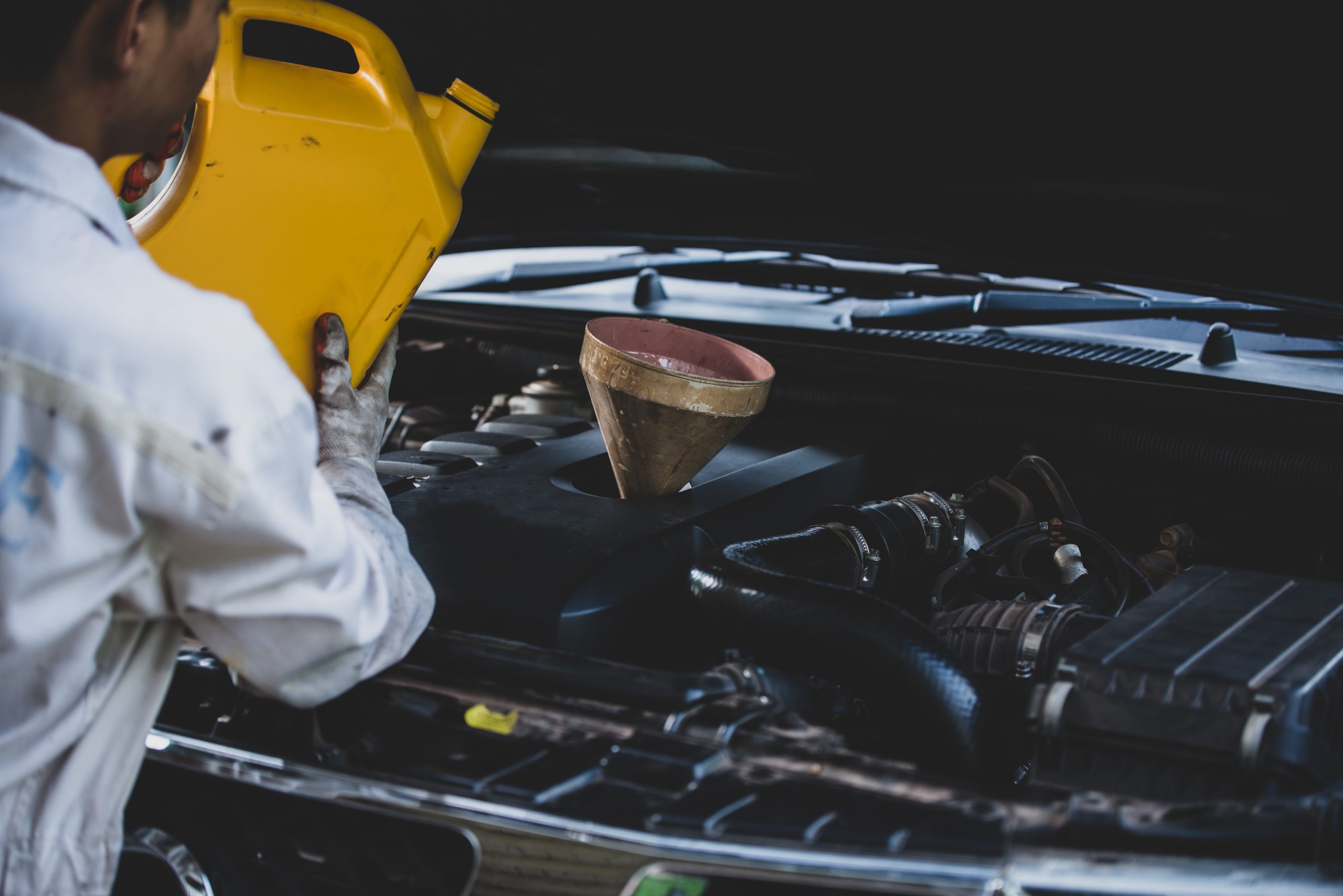Close-up of an auto mechanic pouring fresh oil into a car engine during an oil change and lube service