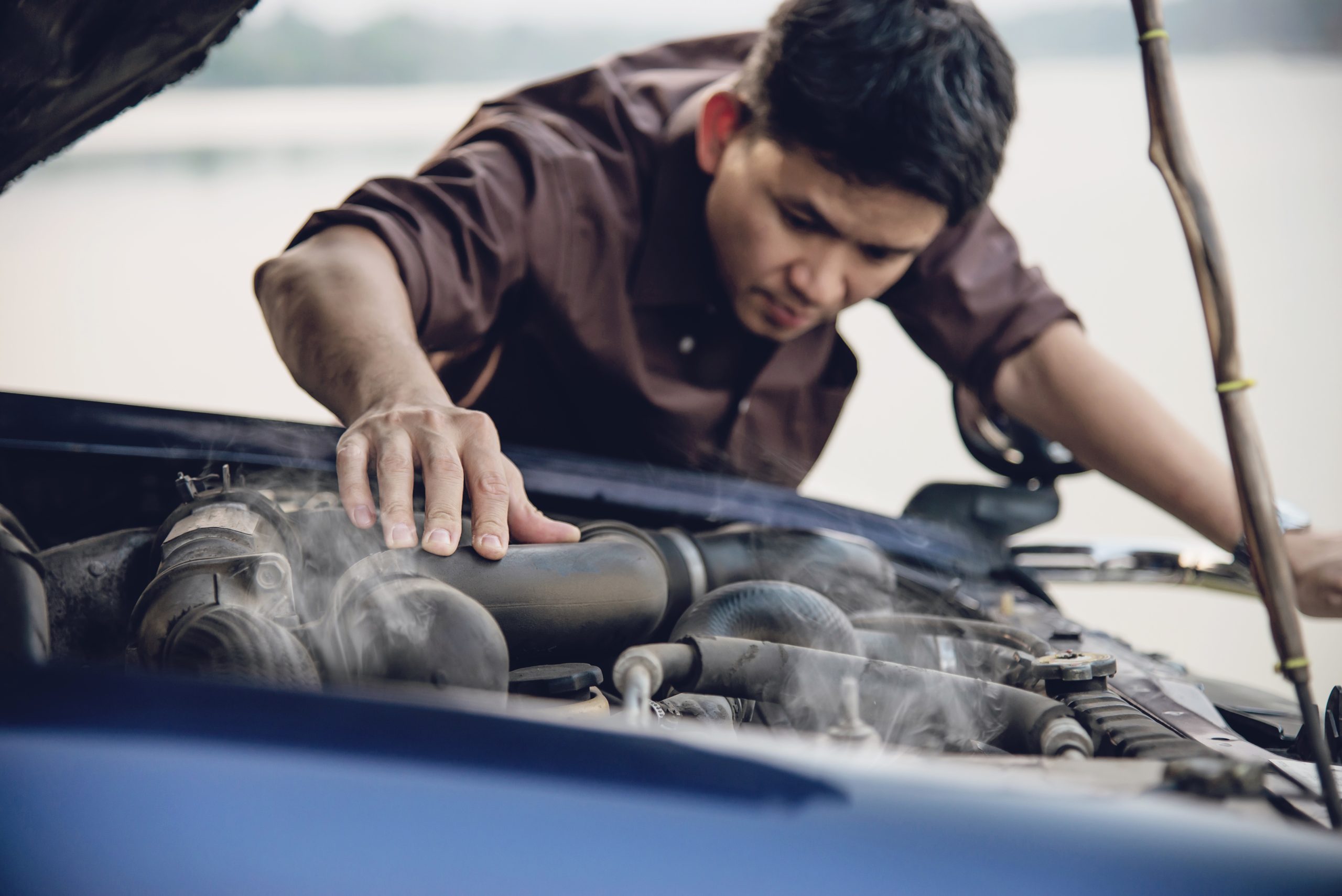 Driver inspecting engine bay for transmission overheating issues in Nampa, ID