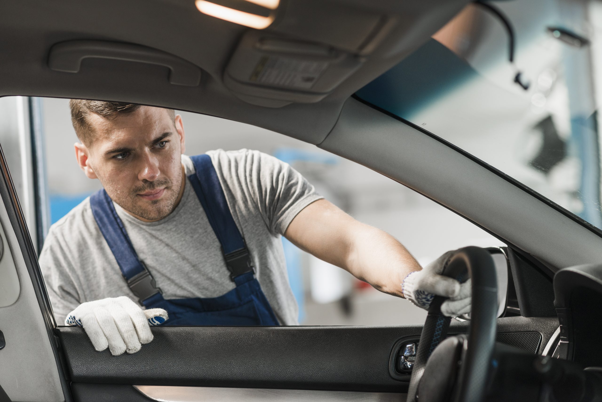 Auto mechanic inspecting interior components during power window repair in Nampa, ID